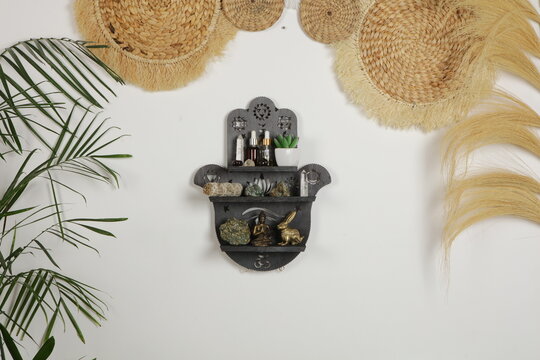 Intricate carved Hamsa Hand floating shelf on a white wall, celestial and esoteric interior design with lunar and solar symbols