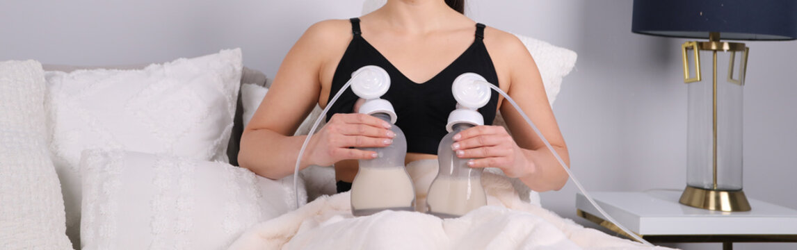 Mother using a double electric breast pump while sitting in bed, concept of modern motherhood and nursing support