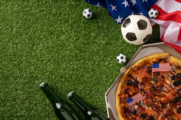 Naklejka premium Football championship party with pizza, American flag, soccer ball and beer on green turf