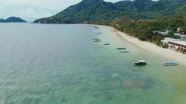 Serene Island Beach With Boats. Idyllic Tropical Shoreline Showcasing Gentle Surf And Lush Greenery