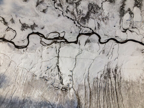 Aerial view of the snow-covered terrain of Babusar Pass with a winding dark river and small remote settlements Babusar, KPK, Pakistan.