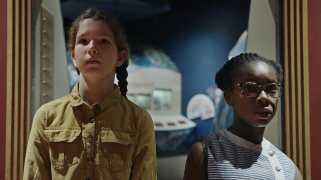 Two young diverse friends looking with wonder at a space exploration exhibit in a science museum