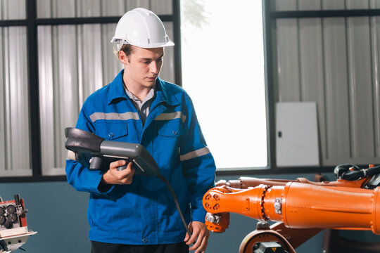 Robot operator control panel auto production factory worker safety helmet engineering inspection industrial technology automation arm modern workplace professional focus