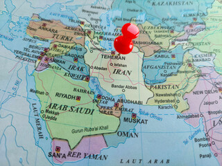 Obraz premium Red pushpin, pinned near Tehran on world map in Indonesian language, highlighting Iran among other countries in the Middle East, for geography, geopolitics, international relations, borders concepts.