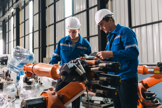 Robot arm worker engineer auto manufacturing factory teamwork inspection industrial technology safety helmet uniform mechanic technician man machine automation modern equipment assembly line
