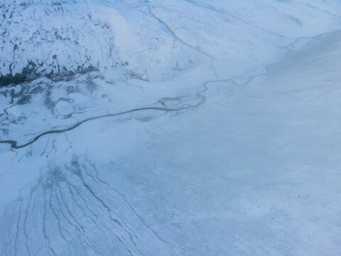 Aerial view of Babusar Pass with a winding river flowing through the snow-covered mountain landscape in Babusar, KPK, Pakistan.