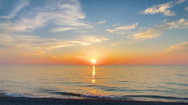 Waves is crashing on the pebble beach. Amazing dramatic sunset over the sea surface in the evening - central composition. Many clouds in the sky. Cloudscape, nature and summer concept