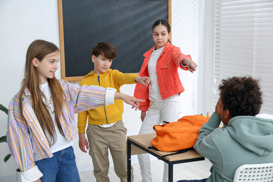 African American boy getting bullied by his classmates in classroom