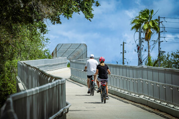 Couple riding bicycles on a paved pedestrian overpass trail on a sunny day, USA © Andrei Liashchou
