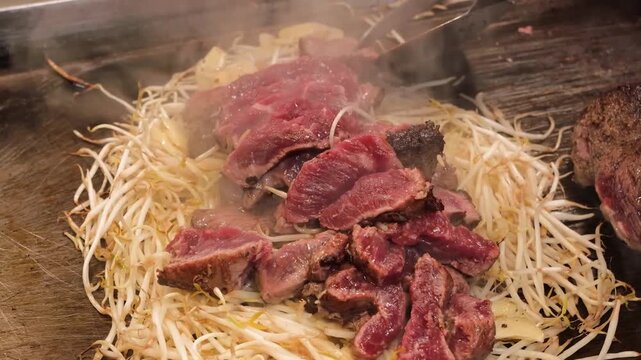 Close-up footage of fresh lamb or mutton being grilled on a traditional dome-shaped iron skillet, known as "Kabuto-nabe," atop a bed of steaming bean sprouts. This iconic Hokkaido soul food dish, call