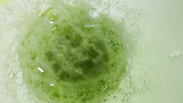 Closeup of green bath bomb spinning and fizzing bubbles