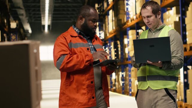 Two employees checking parcel status on package tracking interface, working in industrial depot for import export operations. Efficiency involves coordination and dispatch protocol.