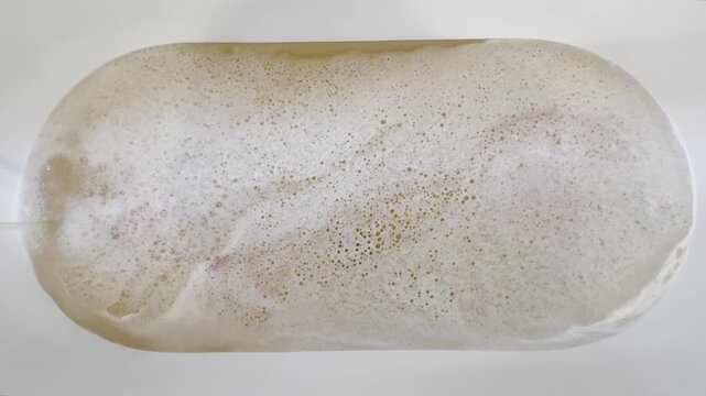 Overhead shot of water filling bathtub full of soapy bubbles