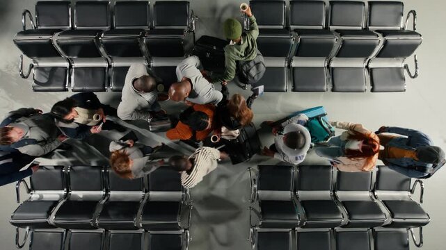 Passengers in busy airport bumping into each other while hurrying to catch plane, top down view. Stressed people rushing in busy departure terminal bashing their trolleys, high angle shot