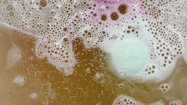 Spinning bath bomb emits fizz and bubbles in bathwater
