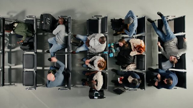 Walking, long flight layover and group of passengers in airport terminal before next departure. Waiting, top down view shot and men with women crowd in busy airport lounge sitting on chairs bench