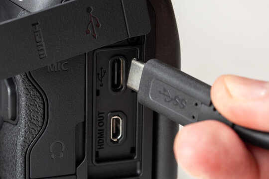 Close-up of a hand connecting a black USB TYPE-C cable to a digital camera interface, macro shot of high-speed data synchronization and professional photography workflow