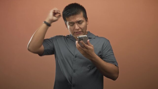 Man holding smartphone and checking the screen, brow furrowed with right hand raised in studio; frustration annoyance confusion.