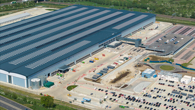 Aerial view of Symmetry Park distribution center featuring a large industrial warehouse with loading bays and parking lots in Kettering, England, United Kingdom.