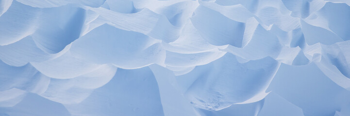Snow texture. Wind sculpted patterns on snow surface. Wind in the tundra and in the mountains on the surface of the snow sculpts patterns and ridges. Arctic, Polar region. Winter panoramic background. © Andrei Stepanov