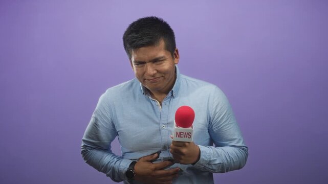 Young hispanic reporter man clutches stomach while holding a red microphone labeled news against a purple studio backdrop, eyes closed and grimacing; duty discomfort.
