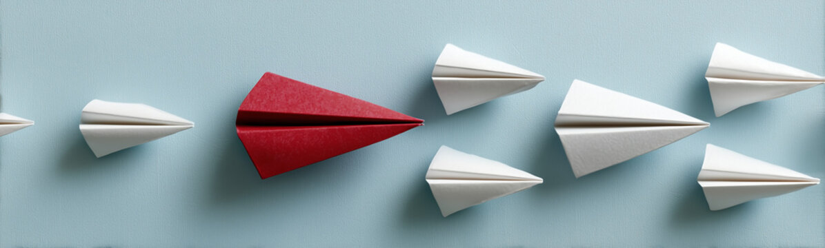 Red Paper Plane: A red paper plane takes flight among a squadron of white paper airplanes, symbolizing leadership, innovation, and standing out from the crowd.