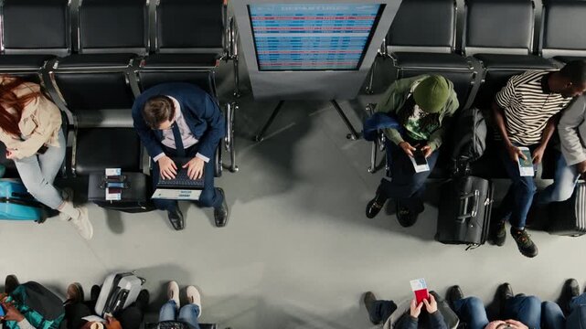 Being late, delayed flights and top down view of upset passengers in airport make telephone calls home to tell bad news. Reacting to flight cancellation red alert, high angle shot and frantic crowd