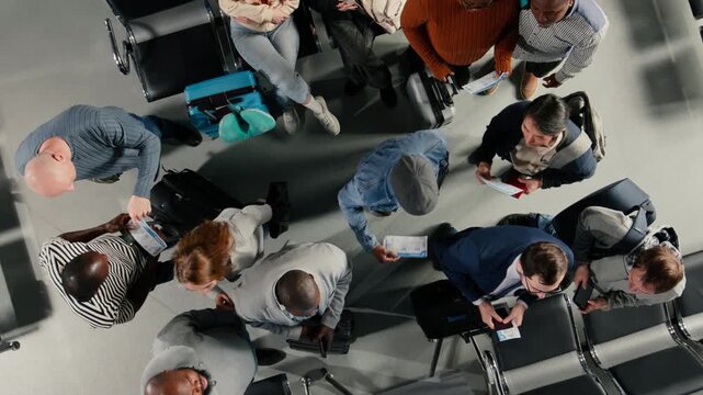 Waiting, top down view and people in airport checking flight schedule screen. Looking at flight timetable display, baggage and passengers in airplane departure terminal, high angle shot