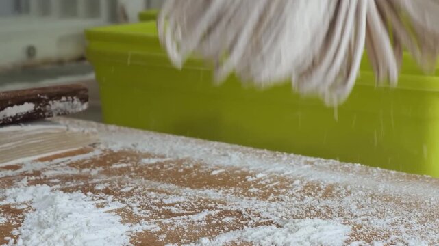 close-up shot of a chef's hands gathering freshly cut, traditional buckwheat soba noodles on a wooden table covered in flour. This footage highlights the authentic, manual process of Japanese noodle-m