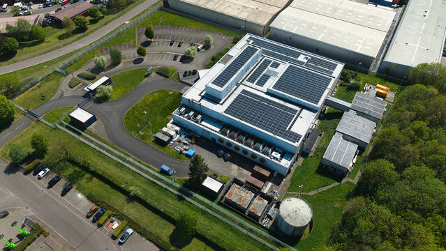 Aerial view of a modern data centre featuring solar panels on the roof, surrounded by green lawns and parking facilities in Wellingborough, England, United Kingdom.