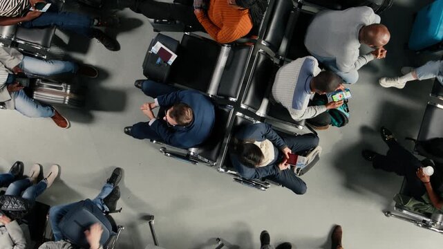Boarding flight, top down view and tourists in airport lounge standing up from chairs, going to departing airplane. Going to boarding gate, high angle shot and passengers leaving airport terminal