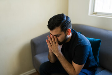 Obraz premium Young man covering face with hands showing sadness, depression, anxiety, despair, and mental health issues