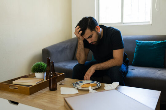 Depressed man experiencing sadness and despair, struggling with mental health issues and alcohol at home