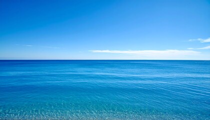 Fototapeta premium Vast expanse of the ocean meets the clear azure sky. A tranquil scene presents a peaceful horizon where blue blends. Waves gently ripple