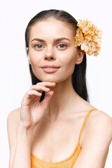 Fototapeta premium Natural beauty portrait of a smiling young woman with a flower, showcasing a fresh and vibrant look in casual summer attire.