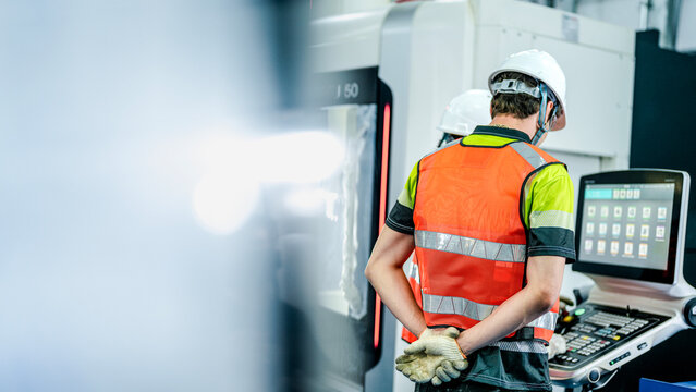 Engineers program an industrial robot or 5-axis CNC machine using an AI interface. The team manufactures advanced microchips or high-tech components in a smart factory.