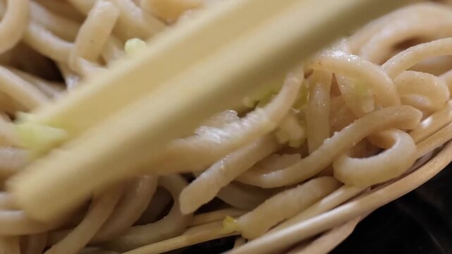 A detailed macro shot of authentic Japanese buckwheat soba noodles, showcasing their earthy texture and tan color. The noodles are topped with a small portion of freshly grated green wasabi or minced 
