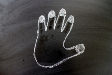 Naklejka premium Outline of a Human Hand Traced in White Chalk on a Blackboard