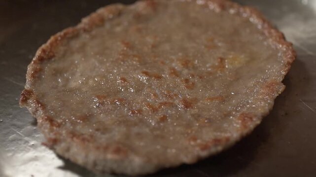 The oil on the surface of an almost cooked milanesa is bubbling. Slowly, this oil cooks a brown milanesa, nearly done to perfection.
