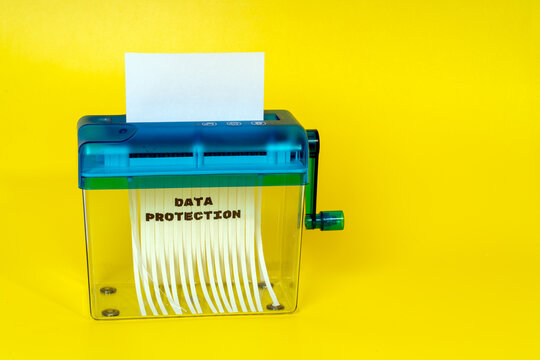 Paper shredder shredding confidential document for data protection concept on yellow background
