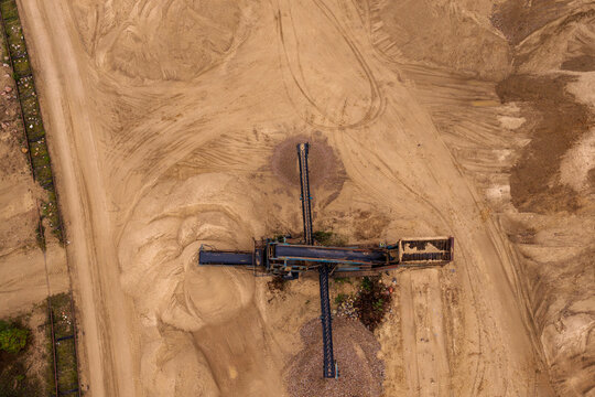 Aerial view of industrial machinery and conveyor belts operating in a sand quarry with large piles of earth and tire tracks Nemencine, Vilnius County, Lithuania.