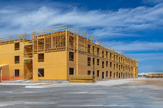 Large multi-story wooden framing at a residential construction site under a blue sky in Florida, USA