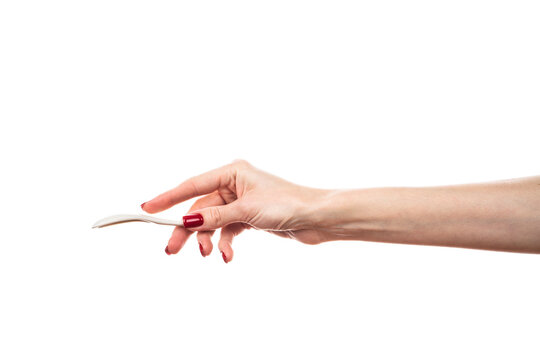 White ceramic tea spoon in female hand isolated on white background.