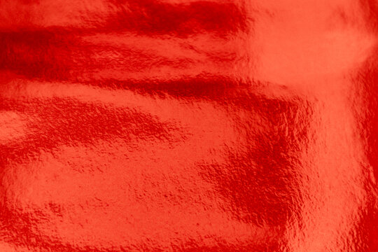 Shiny Red foil texture background with uneven surface. Abstract red orange foil background, metal texture wallpaper