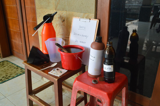 Quarter-right high-angle perspective of a microbial solution preparation station. Featuring bottles of molasses and microbes alongside a syringe and measuring cup for precise dosing.