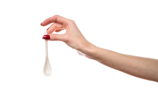 White ceramic tea spoon in female hand isolated on white background.