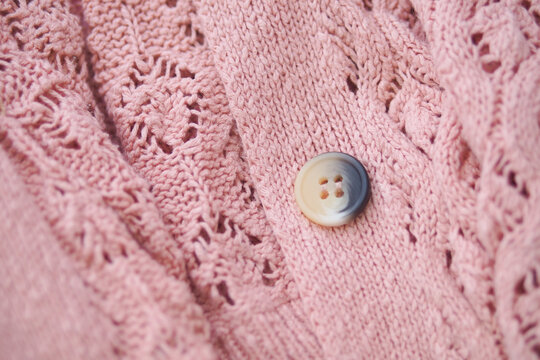 Knitted pink sweater with button detail close up