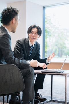 オフィスラウンジで商談する営業社員の法人提案ビジネスイメージ　不動産や士業などの少し堅い仕事のイメージ
