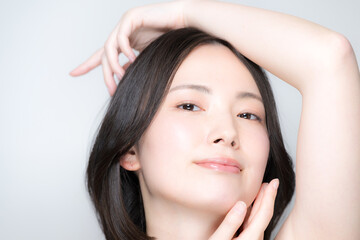Fototapeta premium 透明感ある女性の美容ポートレート美肌とスキンケアビューティー 手と指先、フェイスラインと素肌感が美しいポージングクローズアップカメラ目線