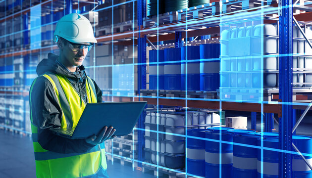 Warehouse inspector monitors chemical storage inventory with laptop.